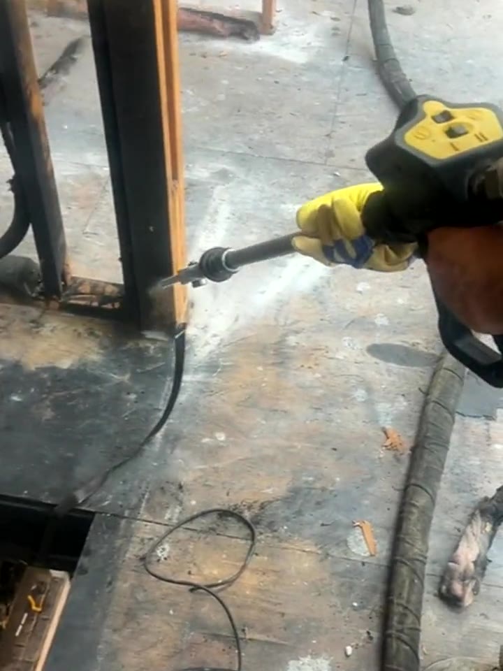 Dry ice nozzle blasting char off a fire-damaged wood stud