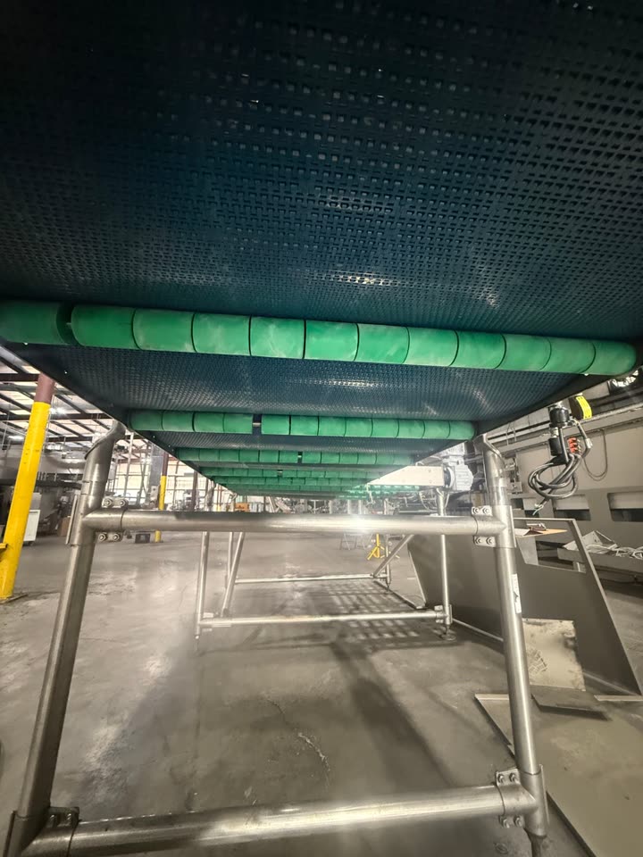 Underside of the same conveyor line with clean green roller drums after dry ice blasting